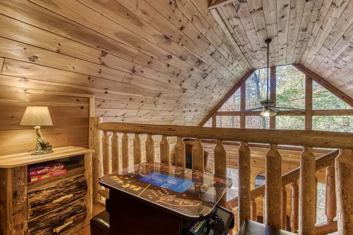 This interior image features a cozy game area with a table set up for board games, a wooden railing, and large windows that fill the space with natural light. The setup suggests a relaxed and inviting environment, perfect for family game nights or friendly competitions.