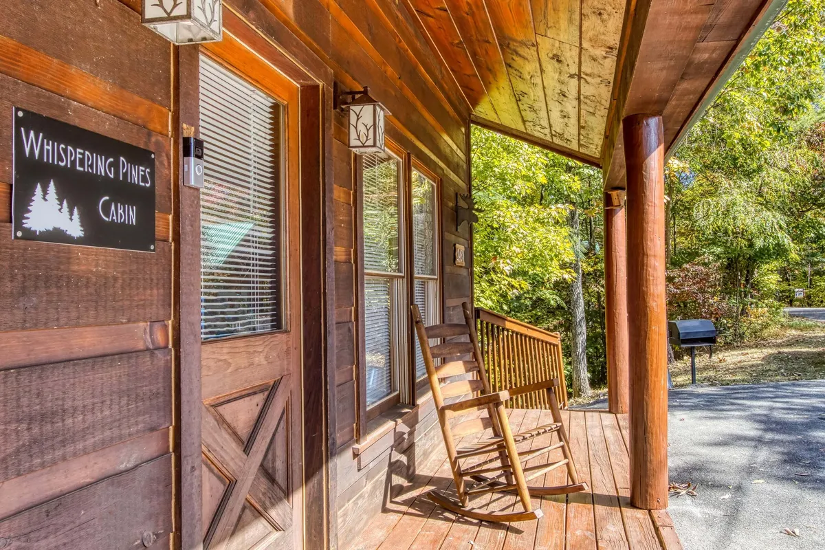 A cozy exterior porch with a wooden rocking chair, cabin sign, and lush greenery around. The scene evokes relaxation and unwinding after a day of activity, with a touch of rustic charm.