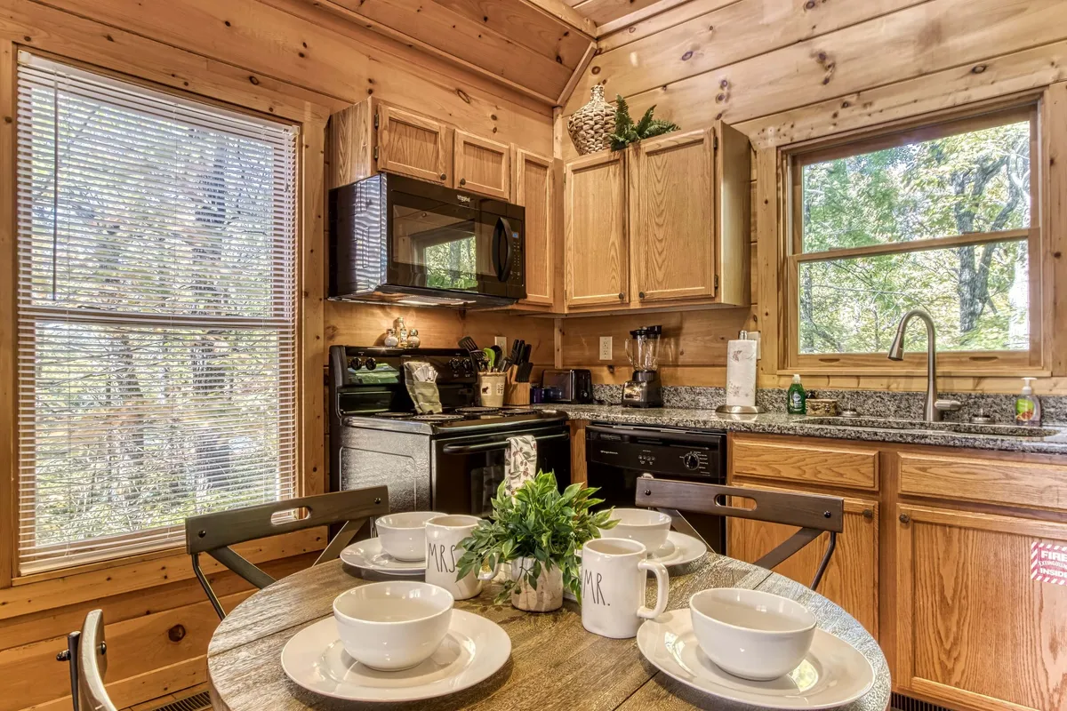 An inviting interior scene with a dining table set for two, surrounded by natural wood finishes and kitchen appliances. The intimate setting suggests socializing, dining, and gathering, echoing the spirit of togetherness and connection highlighted in the section.